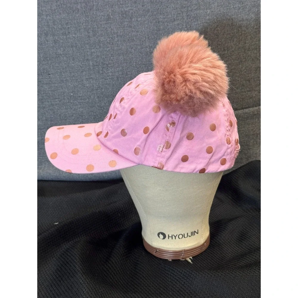 Pink polka-dot cap topped with two fluffy faux fur pom poms